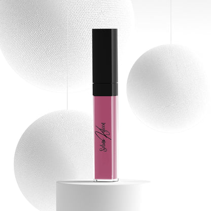 Pink liquid lipstick tube with black cap on white pedestal, modern minimal background