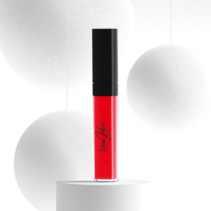 Red liquid lipstick in clear tube with black cap, displayed on white minimal background