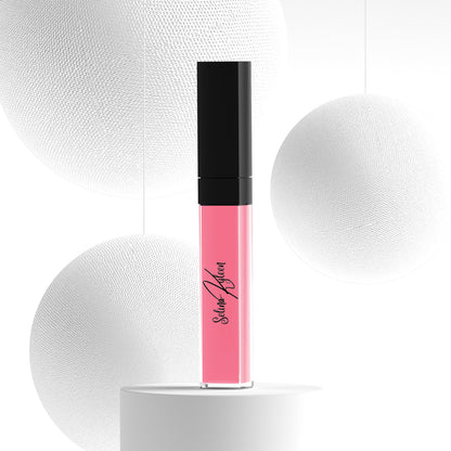 Pink liquid lipstick in clear tube with black cap, displayed on white abstract background