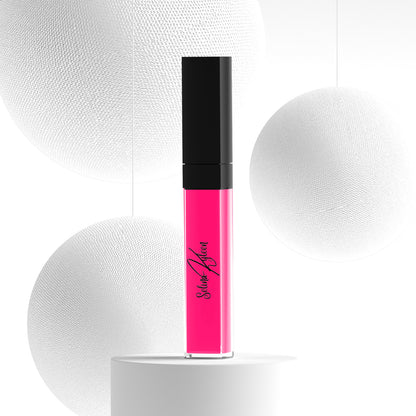 Bright pink liquid lipstick in a clear tube with black cap on a white textured background